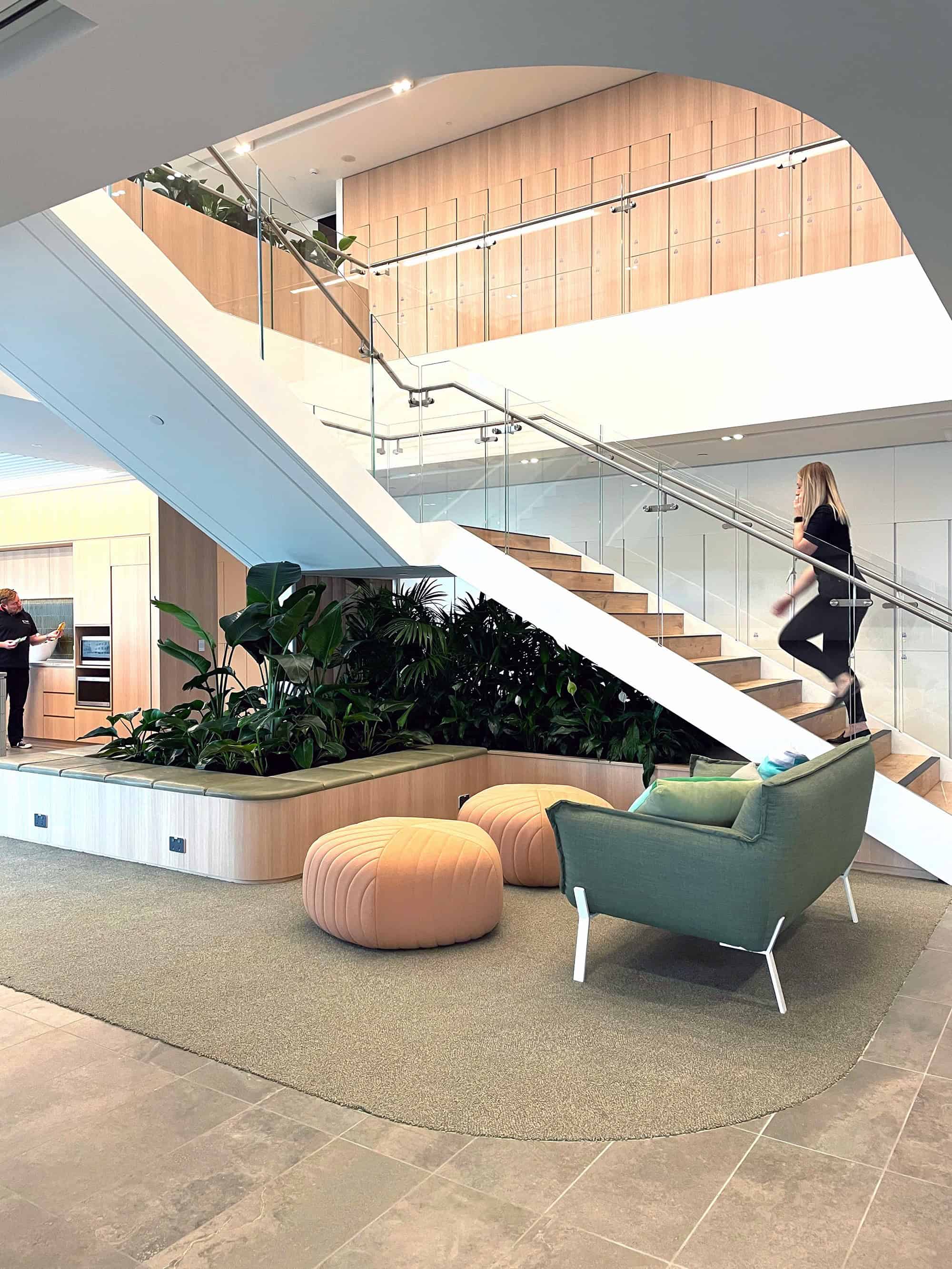 business woman walking up stairs in a corporate building with under the stairs indoor plant arrangement