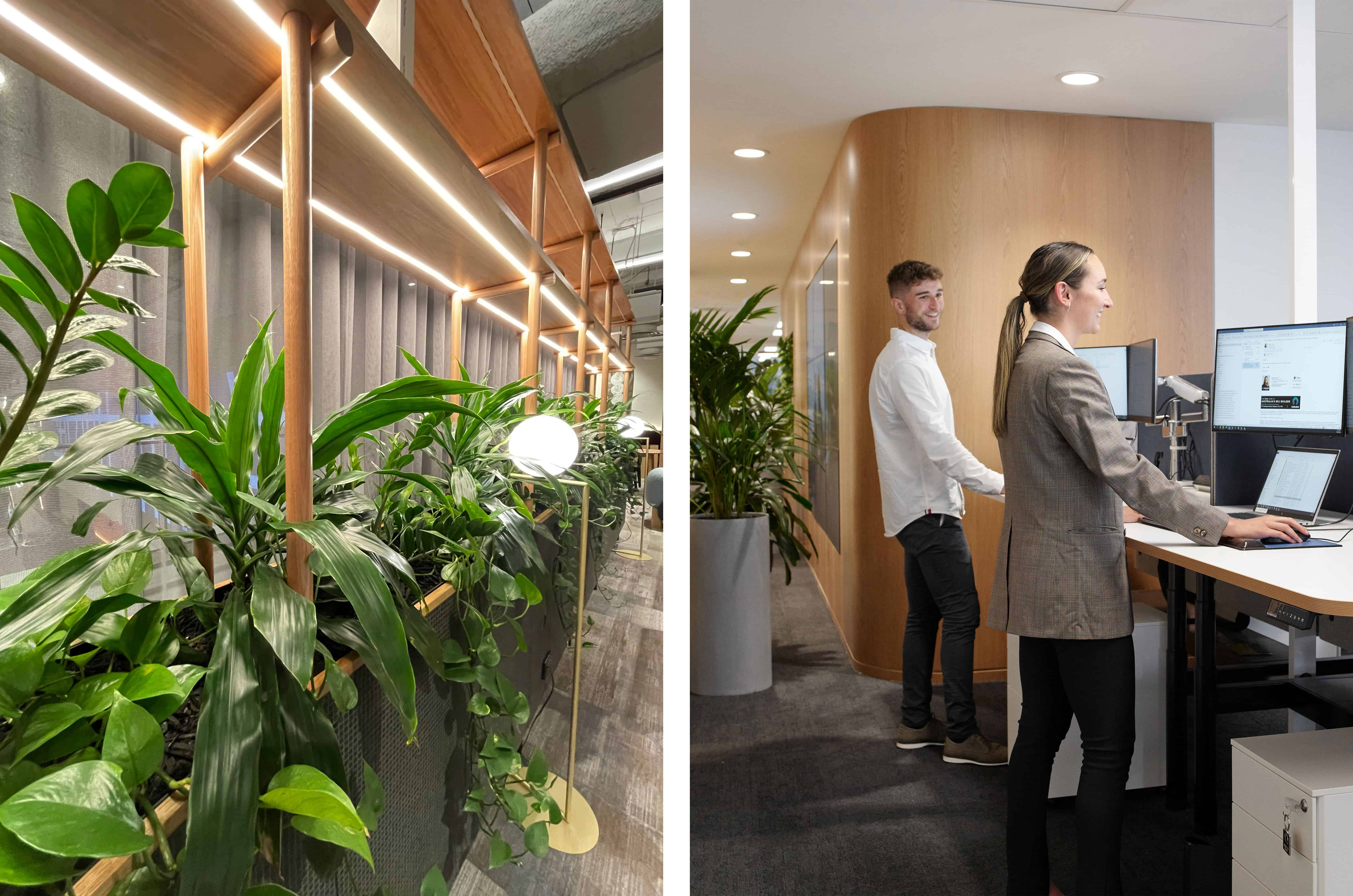 Office plants layered next to two happy employees working a front desk