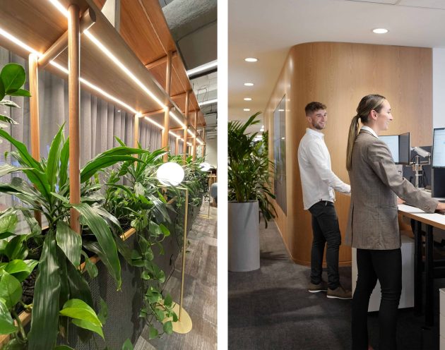 Office plants layered next to two happy employees working a front desk